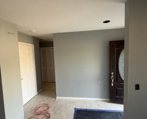 Entry hall painted gray with white closet doors and a dark front door