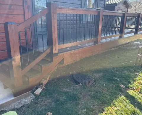 Deck railing and steps finished in a red-brown stain with black metal balusters